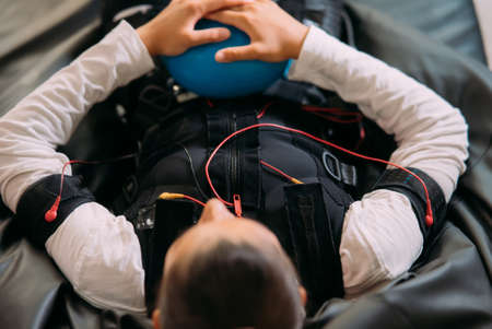 EMS training. The girl lies in a suit with cables.の写真素材