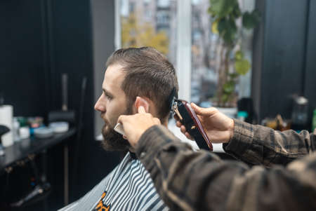 Master in barbershop makes mens haircutting with hair clipperの写真素材