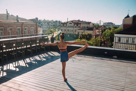 Young woman practicing yoga on the roof of a building