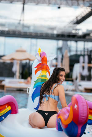Woman on inflatable unicorn toy mattress float in pool.の写真素材