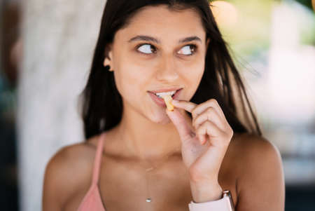 Young woman eating french fries, having her lunch break.の写真素材