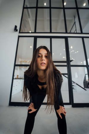 A woman in a black tracksuit leans forward and poses for the camera