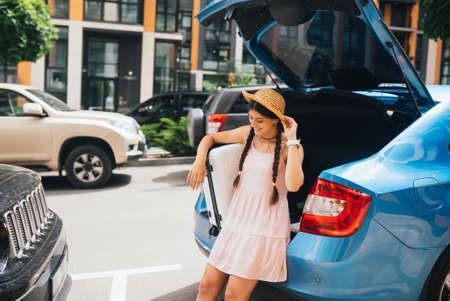 Woman packing her suitcase into luggage boot of the car.の写真素材