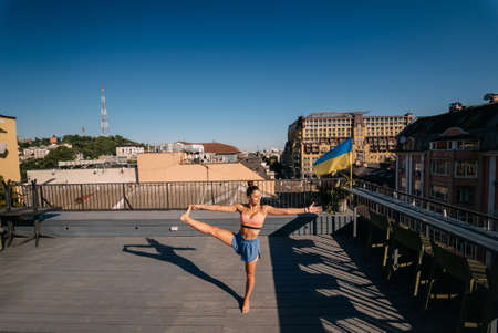 Young woman practicing yoga on the roof of a buildingの写真素材