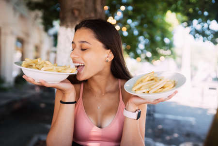 Young women hold french fries on white plates. Street cafeの写真素材