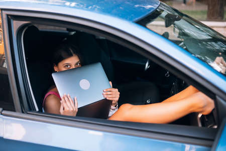 Young woman using laptop in her carの写真素材
