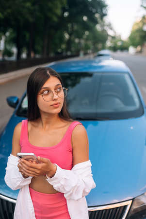 Woman using mobile phone near car at the street
