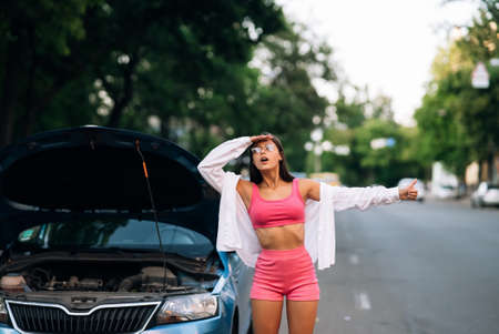 Woman with broken car on the road. Look for help.の写真素材