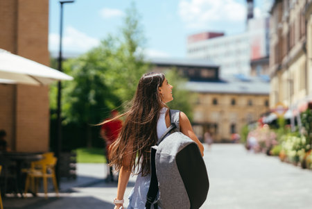 Young woman with backpack walks around the city.