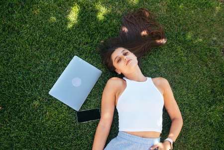 Young fit attractive woman lying on green lawn park.の写真素材