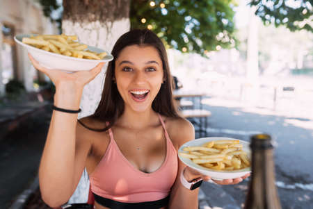 Young women hold french fries on white plates. Street cafeの写真素材