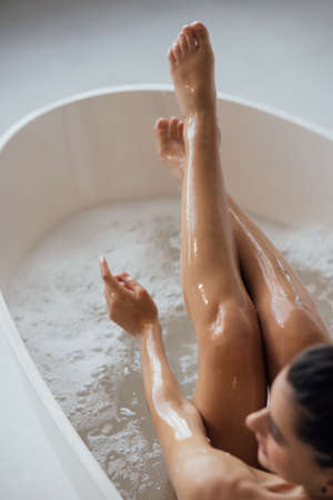Pretty young woman taking bath at home back viewの写真素材