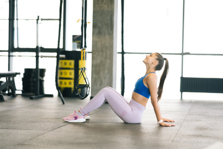 Healthy young female sitting relaxed after training in gym.