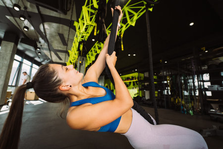 Young woman is climbing a rope in the gym