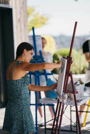 Young woman artist paints with a spatula on the canvasの写真素材