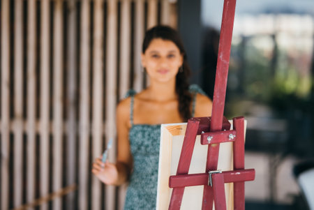 Young woman artist paints with a spatula on the canvasの写真素材