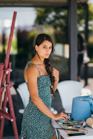 Young woman artist stands close table with a paletteの写真素材