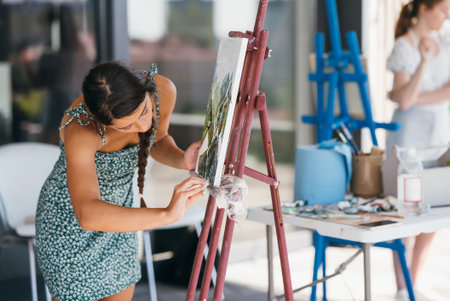 Young woman artist paints with a spatula on the canvasの写真素材