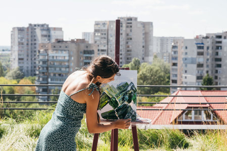 Young artist paints against the background of the cityの写真素材