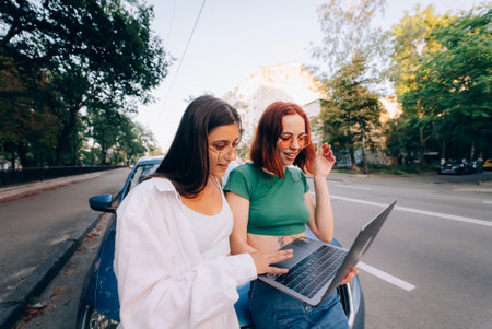 Two young women with a laptop near the carの写真素材