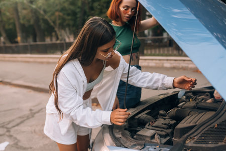 Two women with broken car on the road. Open hoodの写真素材