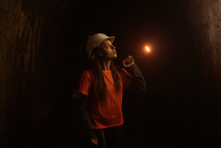 Female digger with flashlight explores the tunnelの写真素材