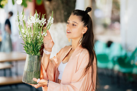 Woman hold a vase of flowers in the street cafeの写真素材