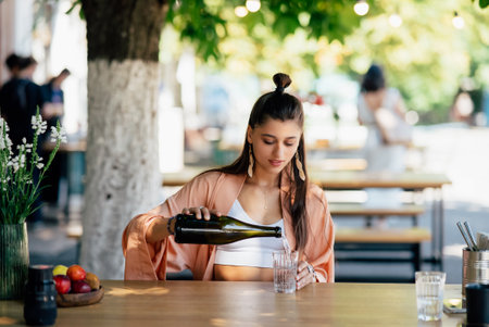 Young woman with a cold drink sitting in a cafe on the streetの写真素材