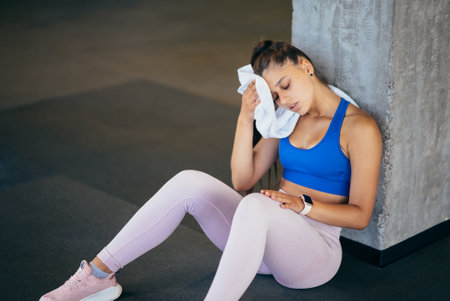 Healthy young female sitting relaxed after training in gym.