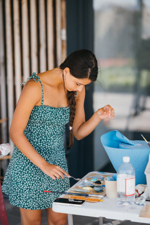Young woman artist stands close table with a palette