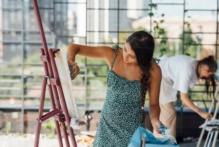 Young woman artist paints with a spatula on the canvasの写真素材