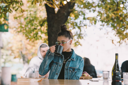 Cute young woman while drinking tea in modern street cafeの写真素材