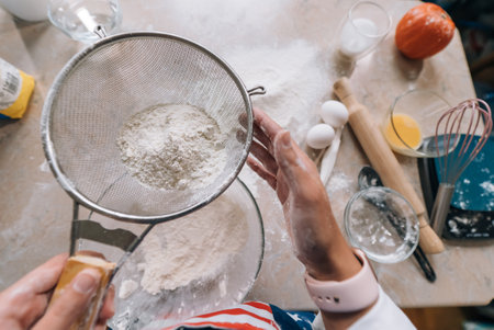 Womans hands sifting flour through sieve. Selective focus.の写真素材