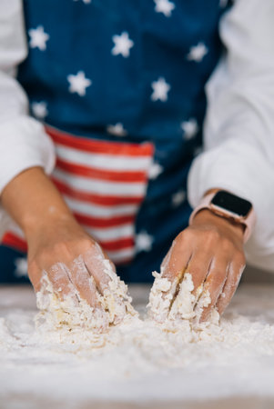 Young housewife in an apron kneads dough with her hands.の写真素材
