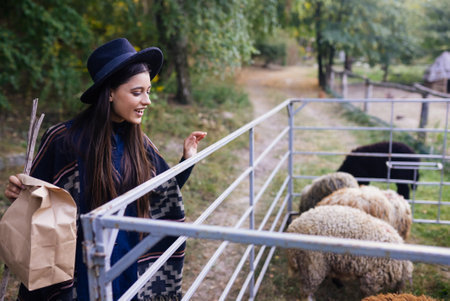 Young woman near a pen with sheep on a farmの写真素材