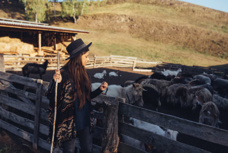 A young beautiful woman near a pen with goats