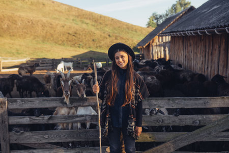 A young beautiful woman near a pen with goatsの写真素材