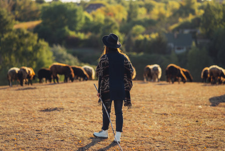 Female shepherd and flock of sheep at a lawn