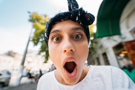 Close up of attractive young woman standing shocked, surprised outdoorの写真素材