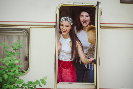 Happy hippie friends are having a good time together in camper trailer. Holiday, vacation, trip concept.の写真素材
