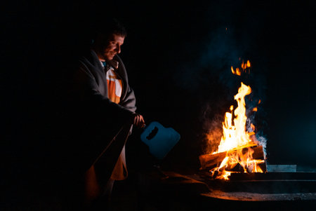 Man preparing bbq grill to cook on fire. Outside dark shot. Freeze moment of fireの写真素材