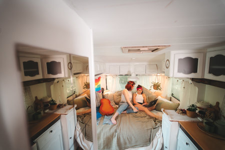 Portrait of a cute lesbian couple. Two girls spend time tenderly together in a camper trailer. Love...