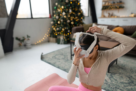 Engaged in yoga, the girl wears pink sportswear and virtual reality glasses.