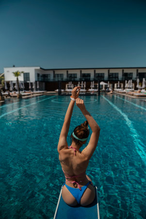 A lovely woman in a swimsuit sits by the pool, facing away from the pool.の写真素材