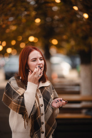 A merry red-haired girl radiates happiness as she walks through the autumn city streets.の写真素材