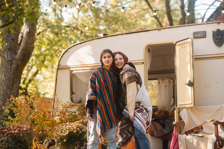 Two stylish girls in hippie attire pose against the backdrop of a trailer.の写真素材