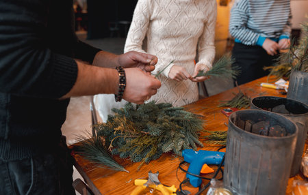 A young woman creating a Christmas wreath at a festive decoration workshop.の写真素材