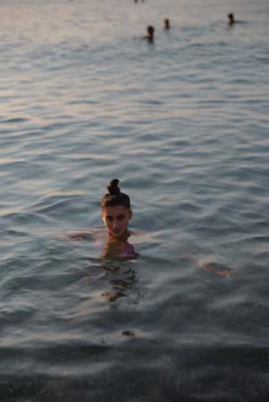 A young girl is swimming joyfully in the serene waters during a beautiful sunset. Theの写真素材