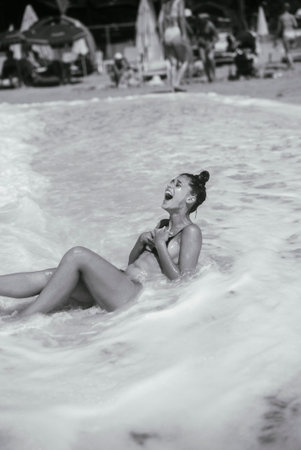 Joyful Beach Moment A Woman Happily Enjoying Waves and the Sun at the Sandy Shorelineの写真素材