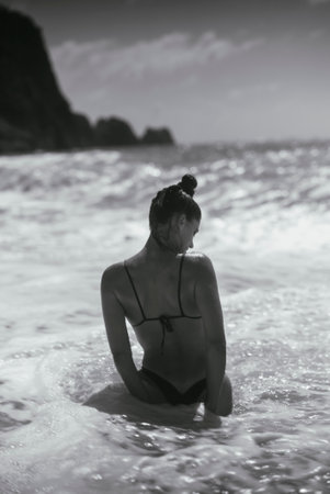A Serene Beach Escape A Woman Enjoying the Waves in Stunning Black and White Photographyの写真素材